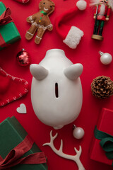 Fototapeta na wymiar Festive Christmas financial savings concept. White piggy bank money box with presents and decorations