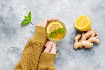 Female hands hold tea with lemon, ginger root and mint leaf © Natureveryday
