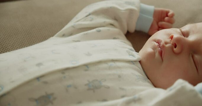 Small baby is sleeping at home.  Infant sleeping at home. Infant sleeping in afternoon. Closeup face of a  small caucasian baby is resting. Slow motion - Cinematic shot of napping child..