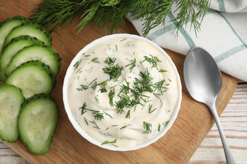 Tasty creamy dill sauce and ingredients on white wooden table, flat lay