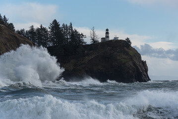 Naklejka na ściany i meble Powerful stormy ocean waves crashing under cliff and light house on the Washington Coast
