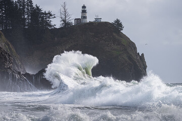 Powerful ocean wave crashing under lighthouse during king tide storms on the Washington coast, Cape...