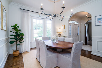 Neutral dining room with 6 light chandelier and arched doorway