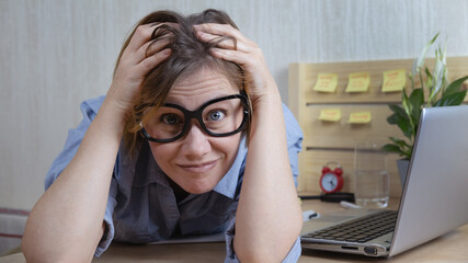A crazy blogger with big glasses holds his head.