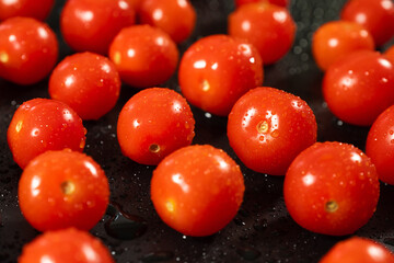 Fresh cherry tomatoes on a black table close-up.