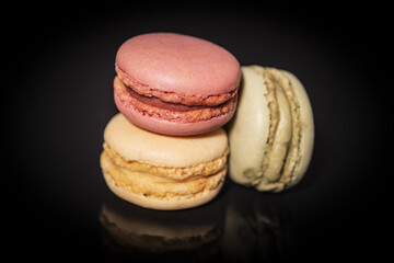 close-up of macarins of various colours on a black background.