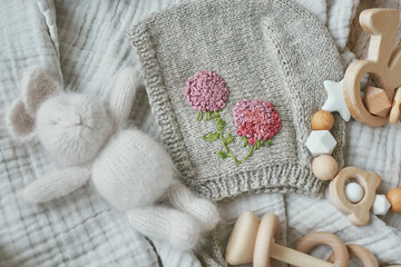 Obraz na płótnie Canvas Hobbies and handicrafts. Knitted beanie with handmade embroidery. Wooden toys, rattles, teethers, nipple holder. Baby development, fine motor skills. Children and newborn products and accessories.