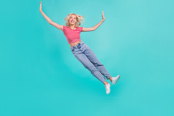 Fototapeta na wymiar Photo of charming funky young lady wear striped t-shirt jumping high falling smiling isolated turquoise color background
