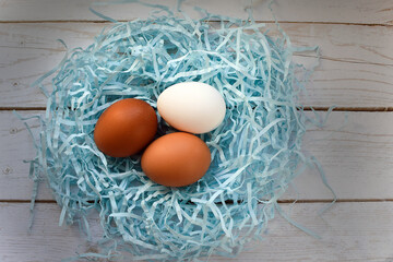 White and brown chicken eggs in soft colored straw in the shape of a bird's nest. Easter holiday concept. Hatching chicken eggs. Top view, flat lay.