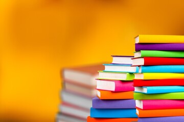 Many stacks of educational books to study in the university library on a color background