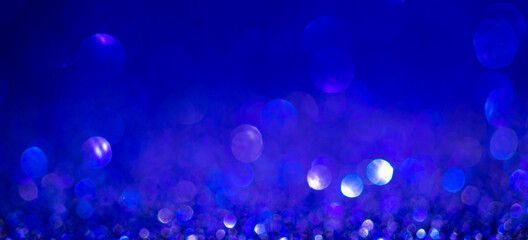 Obraz na płótnie Canvas Indigo blue Christmas lights background, banner design. Shiny glowing surface with bokeh, abstract defocused glitter with sparkles