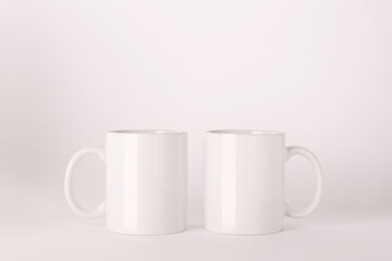 Blank white ceramic mugs on light background