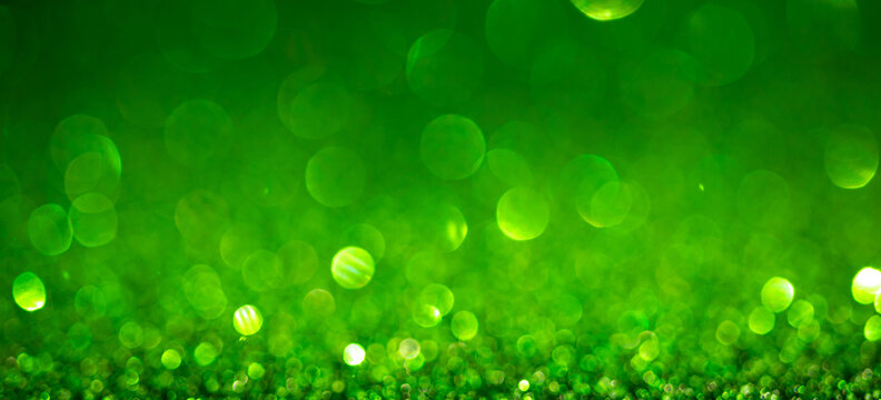Green Christmas lights background, banner design. Shiny glowing surface with bokeh, abstract defocused glitter with sparkles
