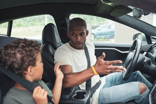 Boy talking with father while sitting in electric car