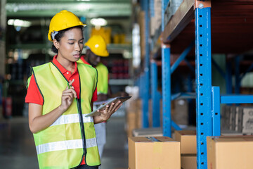 African American woman worker using clipboard working with products or parcel goods on shelf pallet in industrial storage warehouse