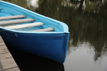 Light blue wooden boat on lake near pier