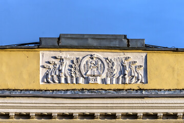 A traditional bas-relief with the coat of arms and banners from the times of the former Soviet Union of the 50s on the facade of an old building.