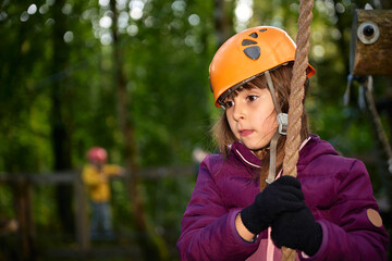 adventure climbing high wire park - kids on course in mountain helmet and safety equipment