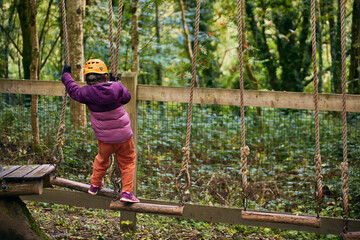 adventure climbing high wire park - kids on course in mountain helmet and safety equipment