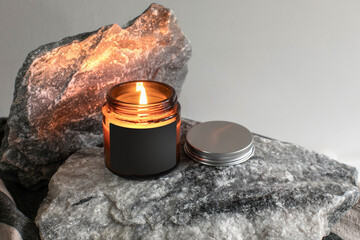 Creative label mockup of the burning handmade candle in glass jar on the marble block background