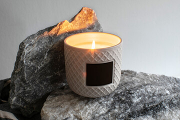 Creative label mockup of the burning handmade candle in ceramic jar on the marble block background