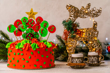 Christmas cake with balls with an inscription in German Frohes Fest Happy holiday deer with garland and coffee cups. Decoration for the holiday. Beautifully served table for the celebration.