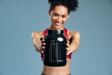 Portrait of sporty beautiful smiling woman in sportswear holding shaker with healthy drink, whey...