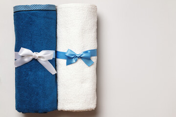 New white and blue terry towels on a light gray background. Top view flat lay copy space