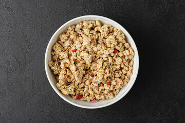 Granola in white bowl on dark table.
