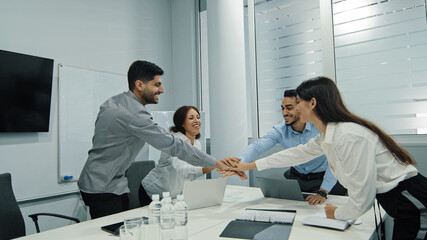 Fototapeta premium Excited multicultural cheerful businesspeople sitting together at meeting giving high five gesture multiethnic colleagues feels happy, showing team spirit, celebrating news victory goal achievement