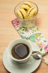 Uma xícara com café e porção de biscoitos amanteigados.