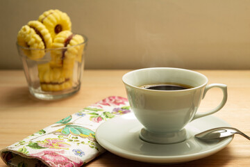Uma xícara com café e porção de biscoitos amanteigados.