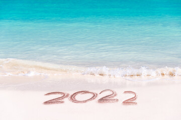 Fototapeta na wymiar 2022 written on the sand of a tropical beach, travel new year card