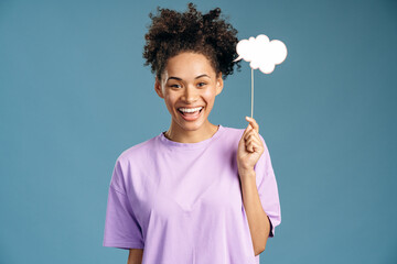 Portrait of happy multiracial curly-haired woman holding paper cloud at the hand
