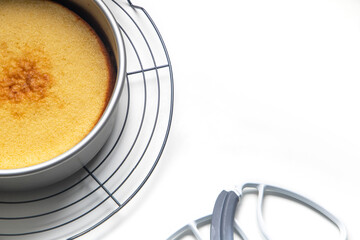 Tarta en molde para horno con utensilios de pasteleria sobre fondo blanco vista desde arriba