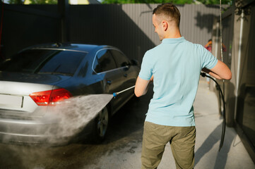 Man holds high pressure water gun, car wash