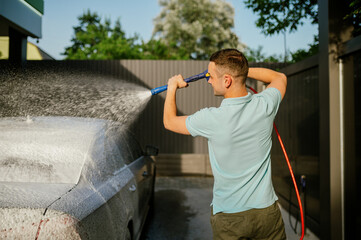 Man using water gun with foam, hand car wash