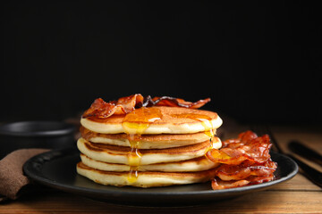 Delicious pancakes with maple syrup and fried bacon on wooden table