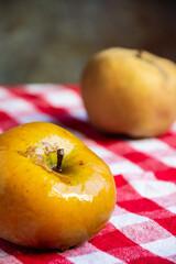 Top view of two pippin apples, on red checkered cloth, selective focus, gray background, vertical, with copy space