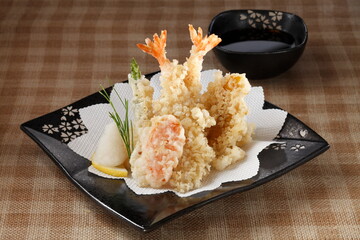 Assorted tempura Japanese food in a plate on tablecloth.