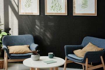Image of modern room with comfortable armchairs and beautiful pictures on the black wall for relaxation