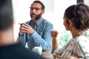 Casual multiage business people working with laptops while talking of they new project together in...