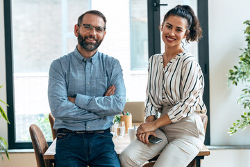 Multiage business people taking a break of work while looking at camera sitting on table at modern startup.