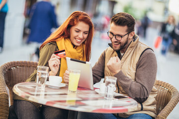 Young couple in a cafe using digital tablet and credit card.