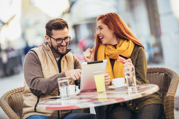 Young couple in a cafe using digital tablet and credit card.