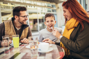 Portrait of happy family spending time in pizzeria outdoors