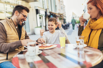 Portrait of happy family spending time in pizzeria outdoors