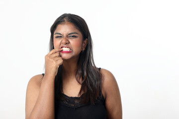 Young attractive Asian Indian woman pose face body expression mode emotion on white background sowing finger in teeth