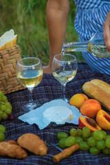 The girl pours wine at a picnic. Selective focus.