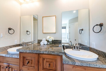 Double vanity sinks with cabinet countertop and picture frame in the middle